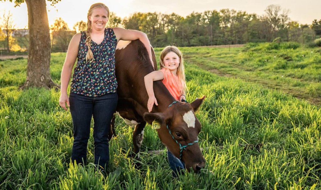 a mom and her daughter pose in front of cows