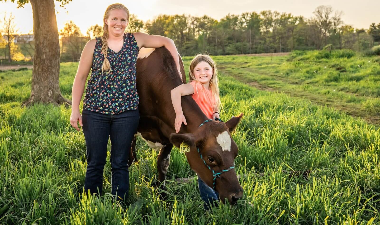 a mom and her daughter pose in front of cows