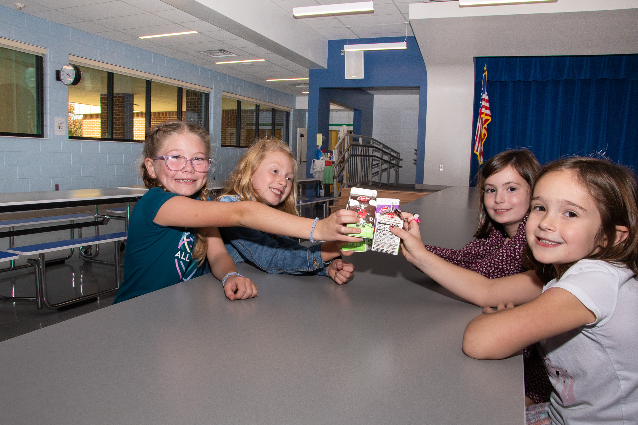 four children bring their milk cartons together in a cheers motion