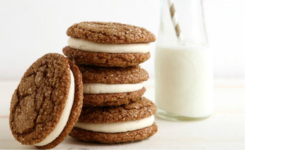 cookie sandwiches next to a glass of milk