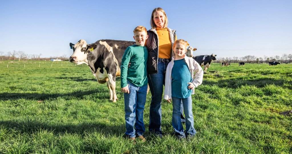 a mom and her two kids pose in front of cows