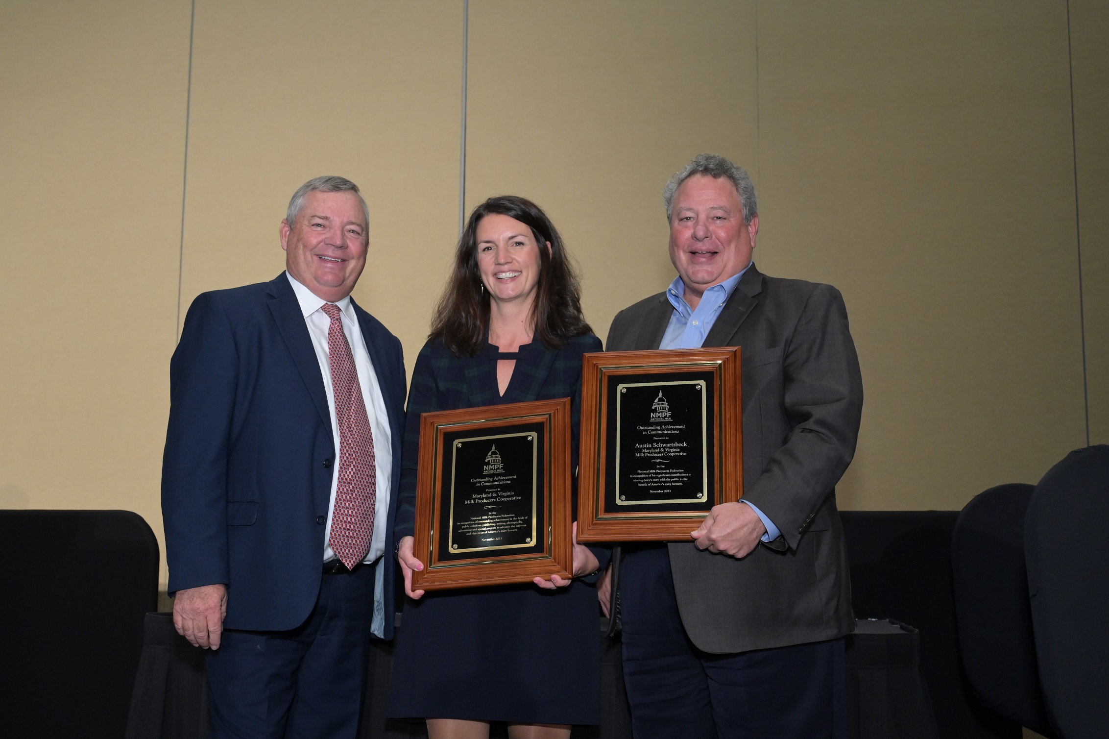 a man and a woman accept plaques from a third man