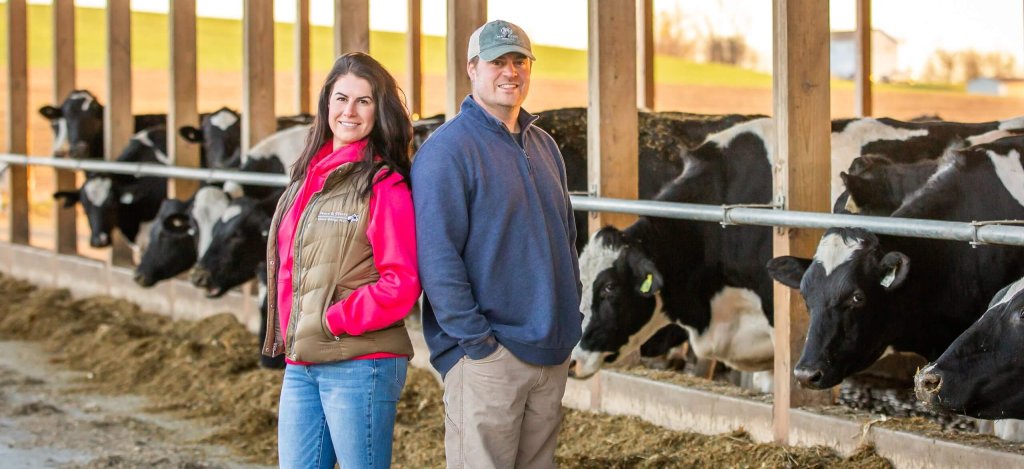 A brother and sister pose together in front of their cows