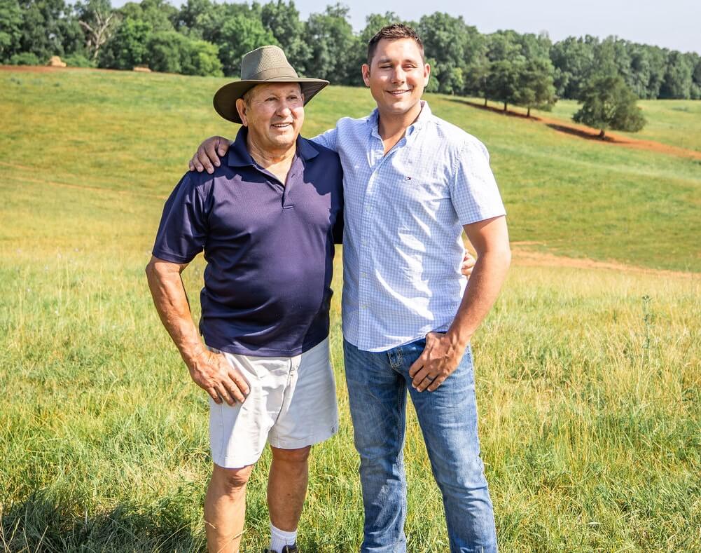 A man and his son stand together in a field